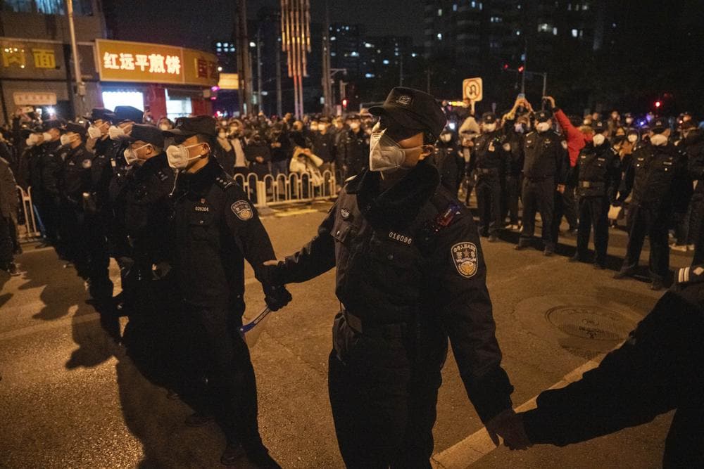 Chinese policemen form a line to stop protesters marching in Beijing, Sunday, Nov. 27, 2022.