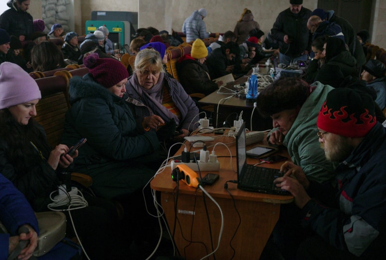 People charge their electronic devices at a railway station after Russia's military retreat from Kherson