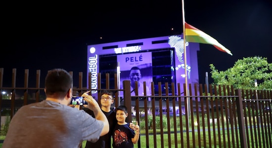 A man takes photos of children with an image of late soccer legend Pele reproduced on the CONMEBOL headquarters building in the background, in Luque, Paraguay A man takes photos of children with an image of late soccer legend Pele reproduced on the CONMEBOL headquarters building in the background, in Luque, Paraguay