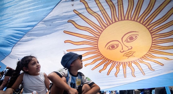 Two young Argentina football fans take shade under the national flag during the team's victory celebrations in  Buenos Aires. (Image: Reuters)