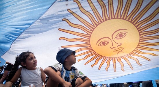 Two young Argentina football fans take shade under the national flag during the team's victory celebrations in Buenos Aires. (Image: Reuters) Two young Argentina football fans take shade under the national flag during the team's victory celebrations in Buenos Aires. (Image: Reuters)