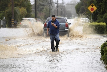 A resident walks along College Road after the area was flooded during a recent storm in Watsonville, Calif., on Monday, Jan. 9, 2023. (Doug Duran/Bay Area News Group via AP)