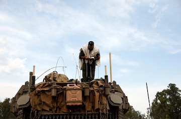 An Israeli soldier prays while he stands on a tank. (Credit: Reuters)